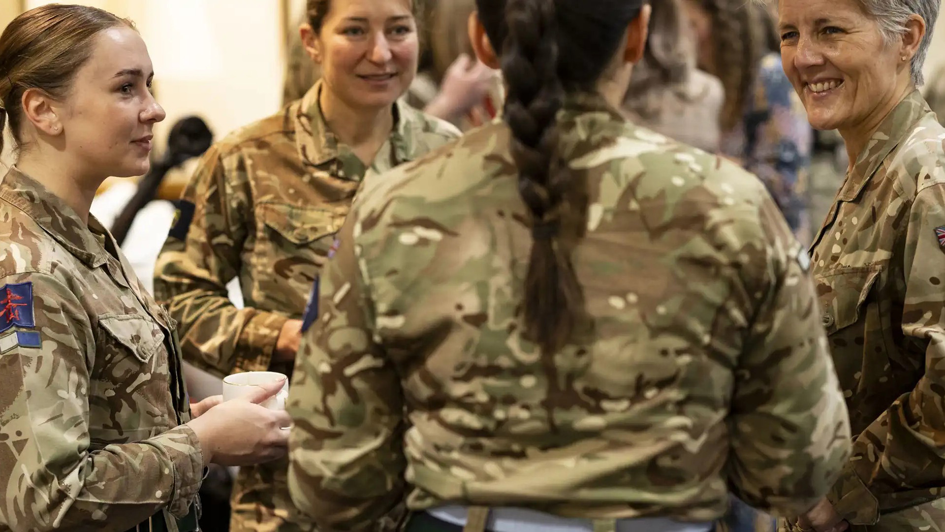 Several servicewomen chat to General Dame Sharon Nesmith over tea and coffee