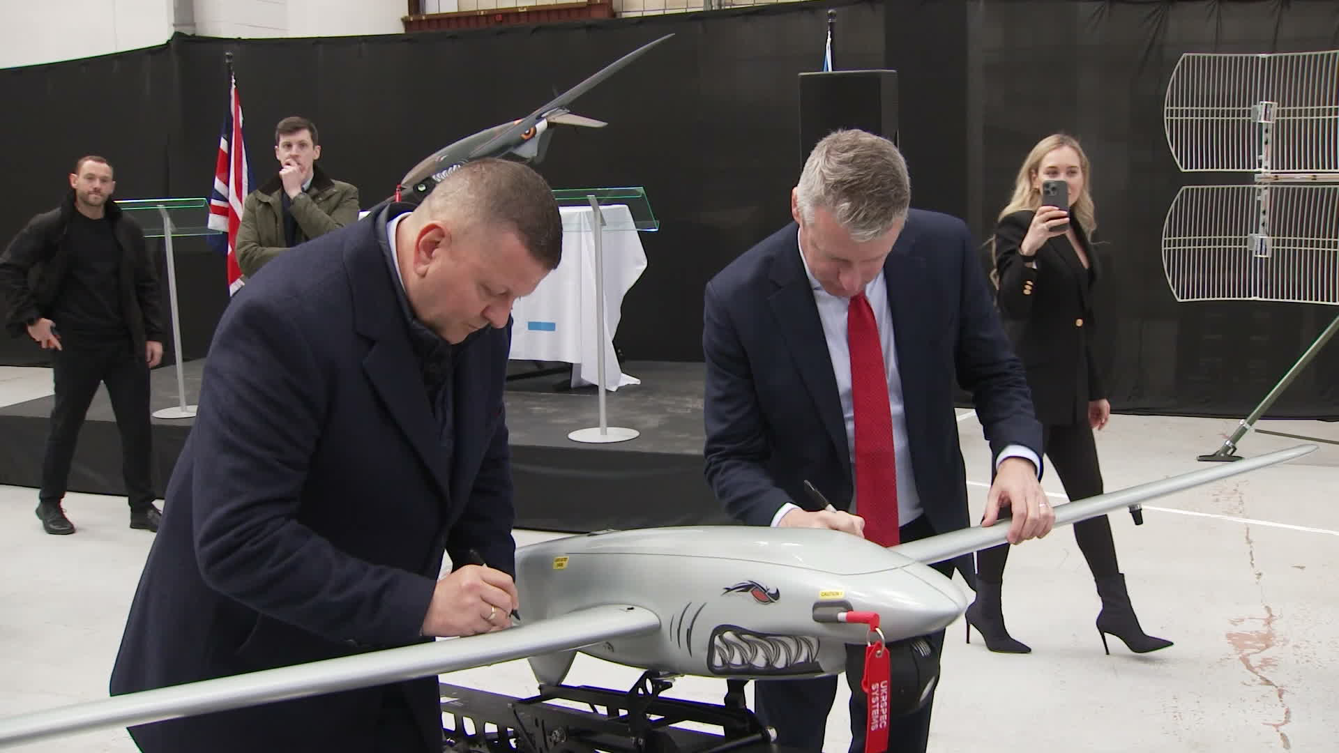General Valerii Zaluzhnyi and Defence Readiness & Industry Minister Luke Pollard autograph the wings of a Shark-M at the Mildenhall site
