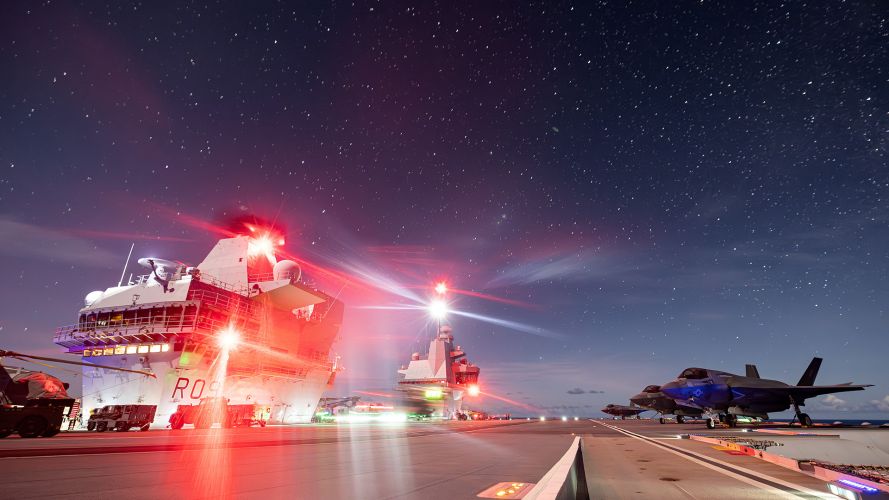 The flight deck of HMS Prince of Wales at night while conducting simultaneous rotary and fixed-wing night flying operations with US F-35s embarked The flight deck of HMS Prince of Wales at night while conducting simultaneous rotary and fixed-wing night flying operations with US F-35s embarked
