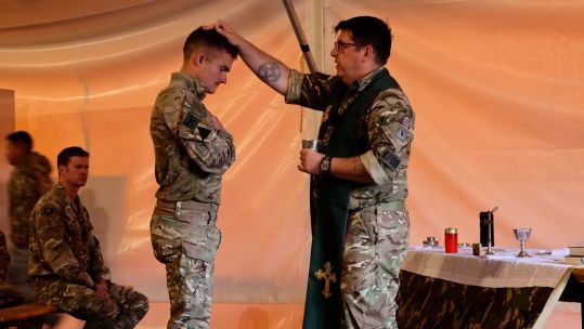 A military padre blesses a KFOR soldier during a field service in Kosovo (Picture: BFBS)