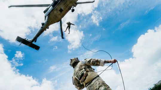 A US Navy explosive ordnance disposal technician secures a rope on the ground for a Peruvian navy counterpart descending from an SH-60 Sea Hawkat Bellows Air Force Station in Hawaii (Picture: US Department of War)