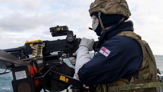 A member of HMS Duncan's upper deck weapons crew loads his GPMG with blank ammunition to practise counter-drone fire