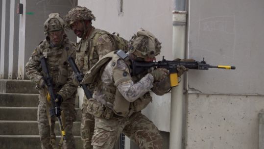 1 Lancs infanteers use the cover of a street corner as they work their way forward, building by building