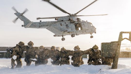 Members of 42 Commando protect themselves from the downwash and whipped up snow after fast-roping from an 845 Naval Air Squadron Merlin Mk4 in Norway