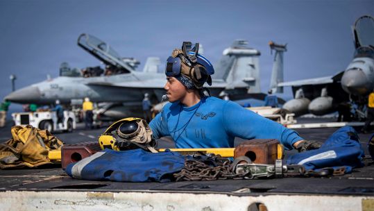 US Navy Aviation Boatswain's Mate Zyrus Rabosa operates a tractor on the flight deck of the USS Abraham Lincoln in the Arabian Sea