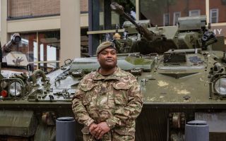 WO1 Beharry stands beside the Warrior infantry fighting vehicle in which he managed to save the lives of his fellow soldiers on two separate occasions (Picture: National Army Museum)