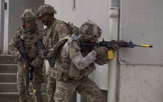1 Lancs infanteers use the cover of a street corner as they work their way forward, building by building