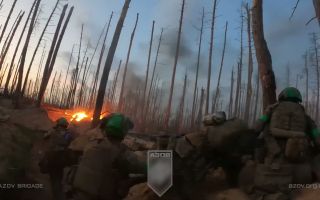 Azov Brigade soldiers stand back as one of their grenades explodes before the move further forward into a Russian trench system